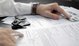 Person pointing at documents with car keys on top of them