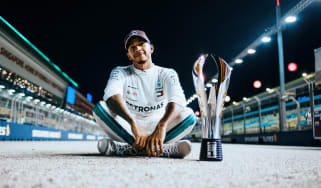 Lewis Hamilton sitting next to a trophy