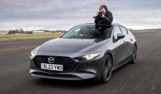 Auto Express senior photographer Pete Gibson taking photos through the Mazda 3&#039;s open sunroof