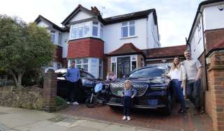 Auto express deputy editor Richard Ingram standing with the Genesis Electrified GV70 and Porsche Cayenne