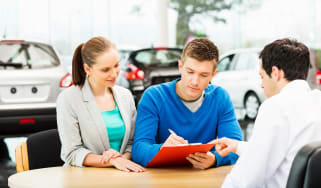 People signing dealership paperwork